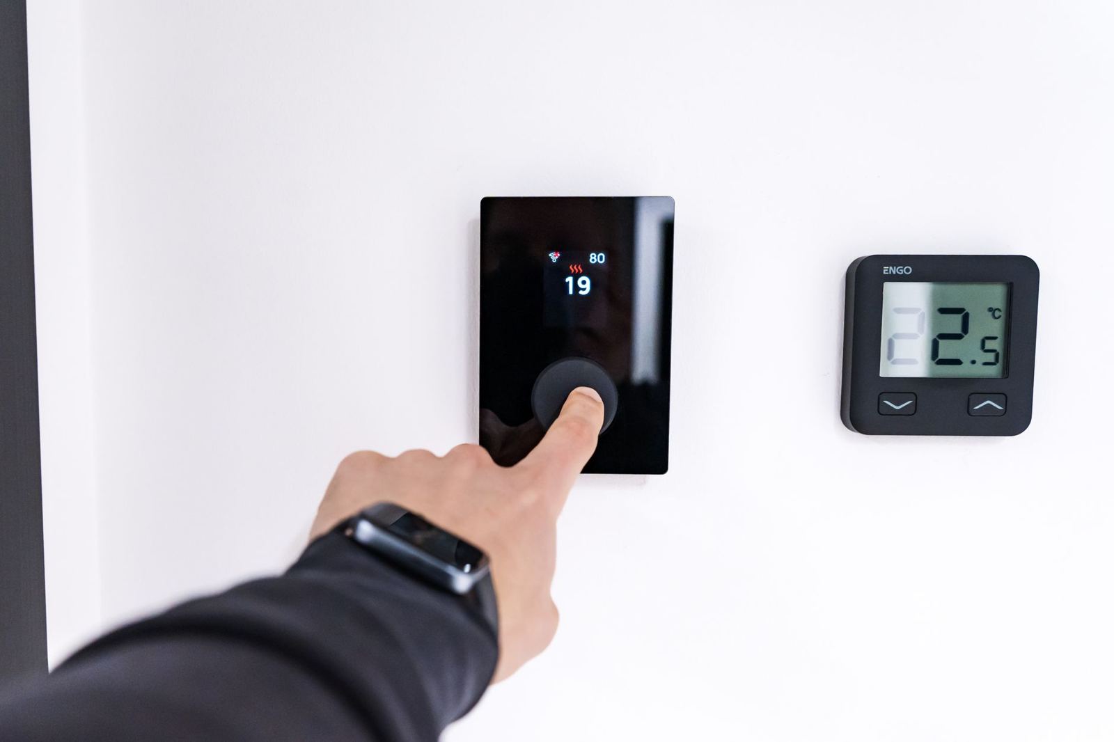 Hand adjusting a wall thermostat to cooling mode