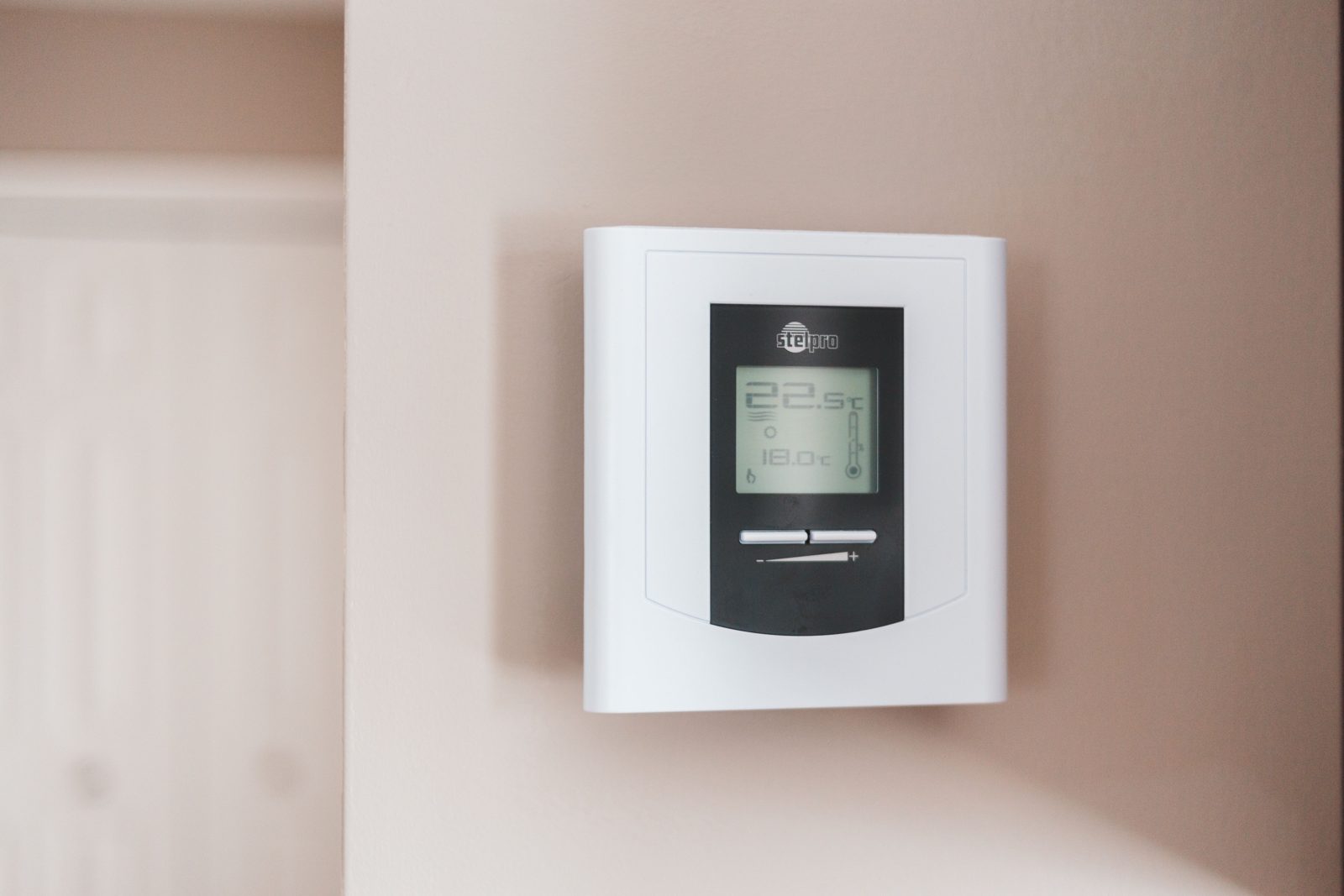 White digital thermostat on a living room wall