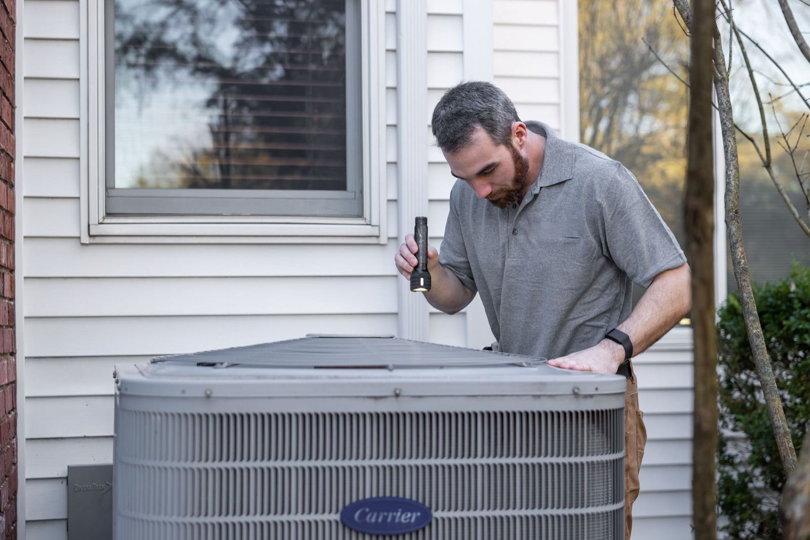Technician inspecting an outdoor AC condenser